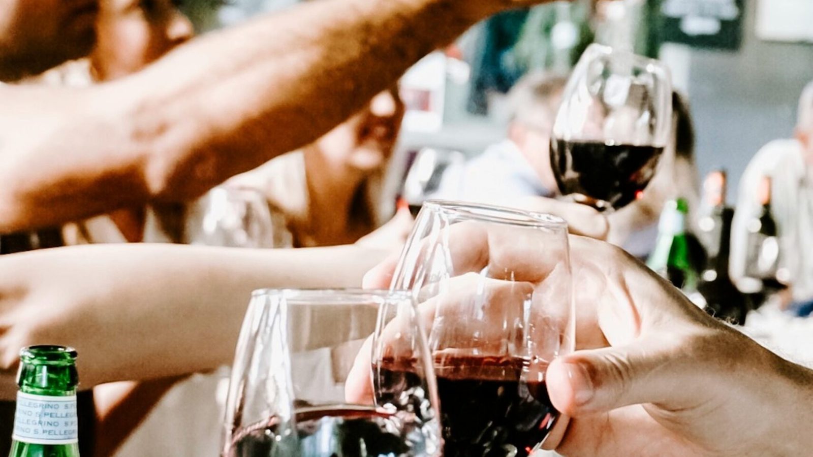 Celebrate with friends during a casual indoor gathering, raising glasses of red wine in a toast.