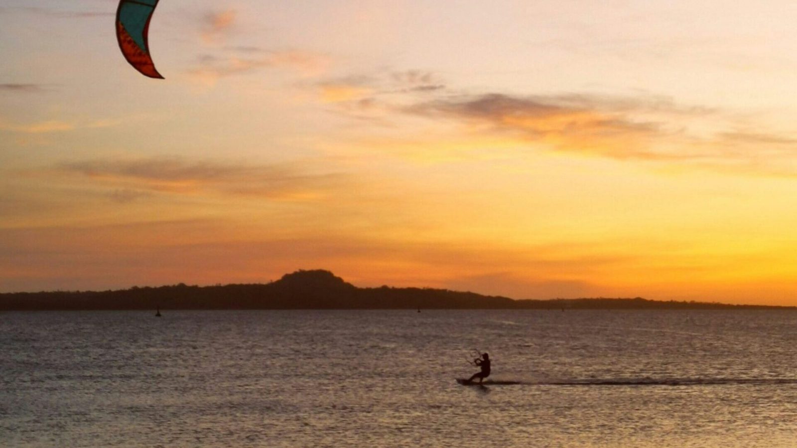 A breathtaking scene of kitesurfing at sunset on a serene sea in Cuyo, Philippines.